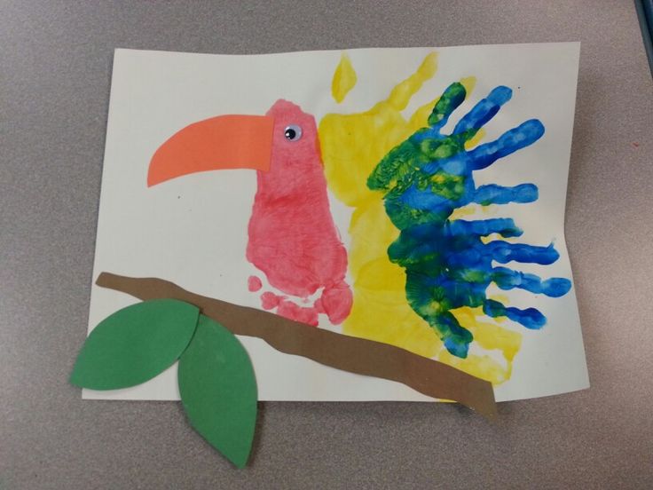 a paper plate with a bird and handprints on it next to a green leaf