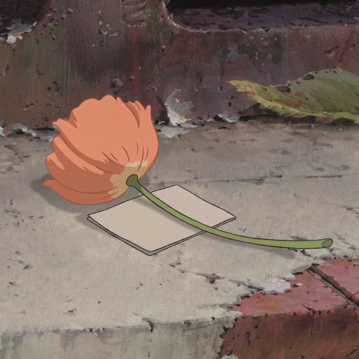 an orange flower sitting on top of a piece of paper next to a brick wall