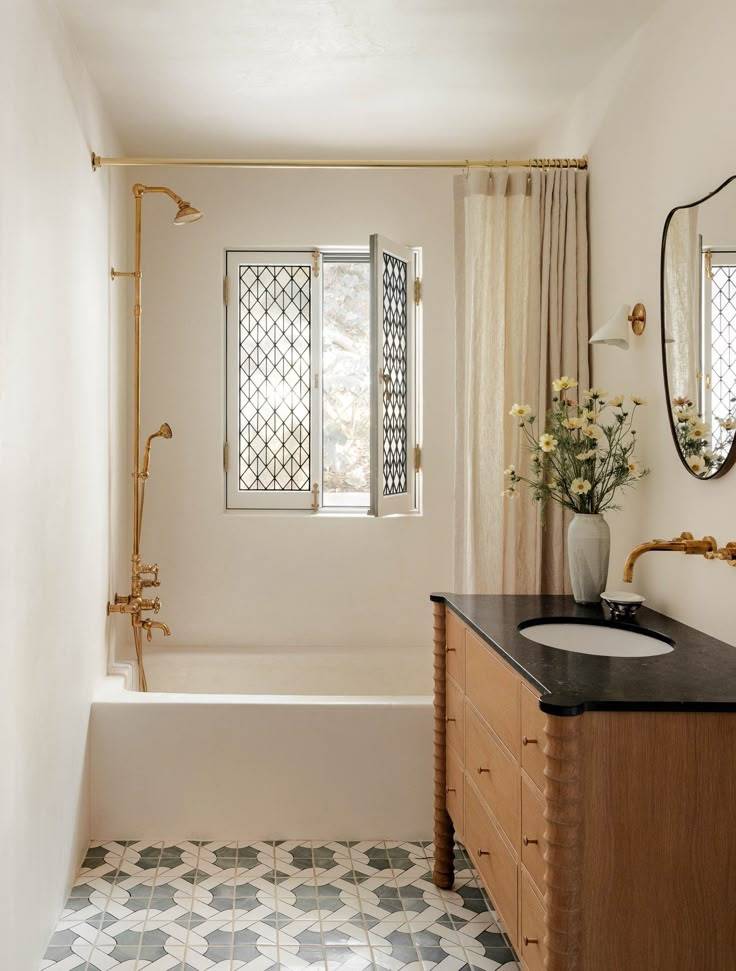 a bathroom with a sink, mirror and bathtub next to a window in the wall