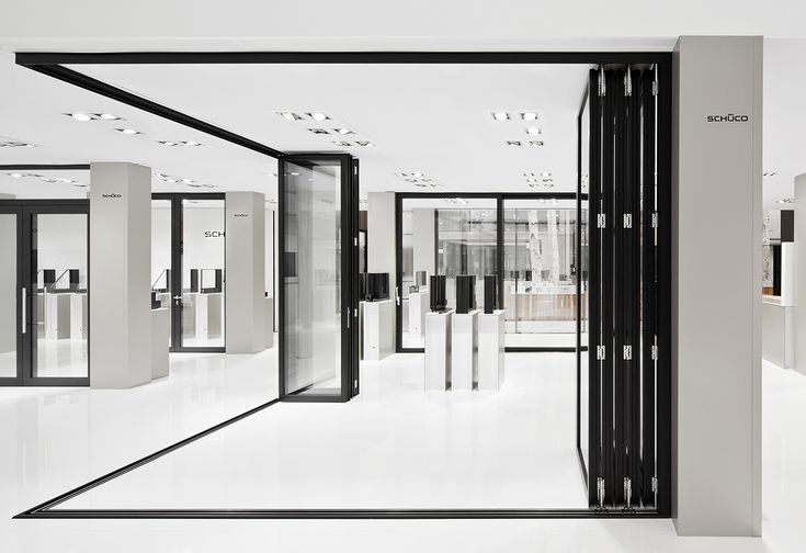 an empty white room with black and silver doors on each side, in the middle of it