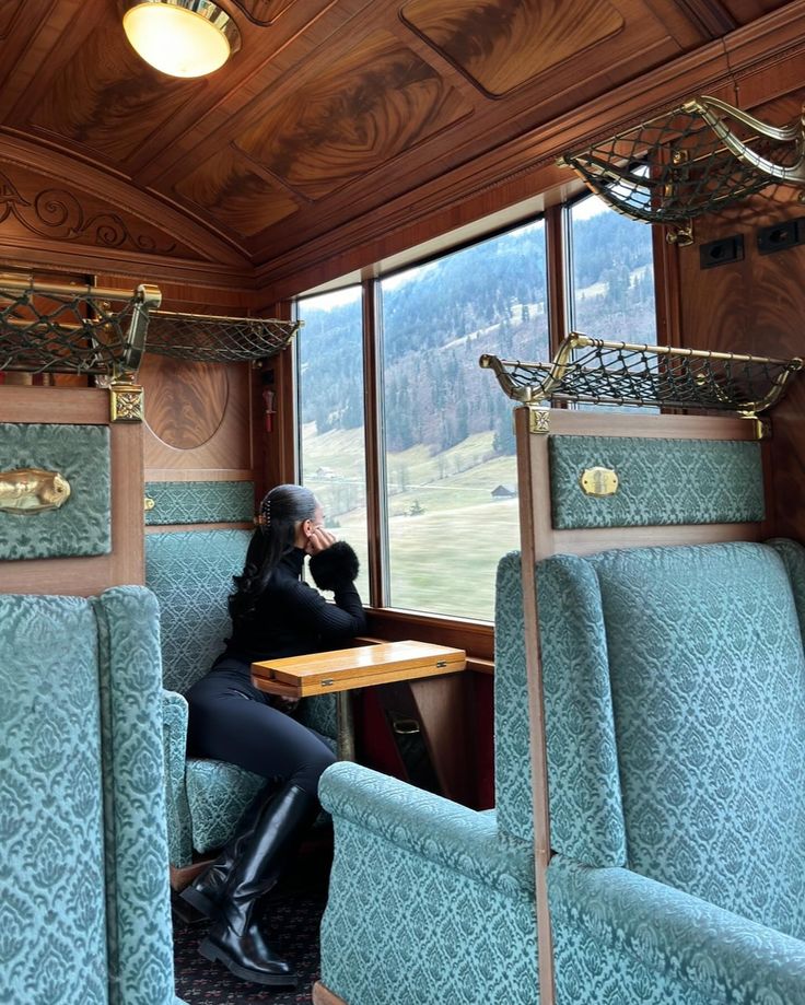 a woman sitting at a table in the middle of a train car with blue seats