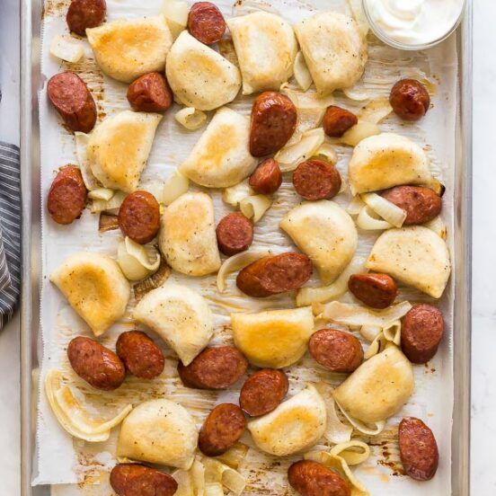 a baking sheet filled with sausage and pasta