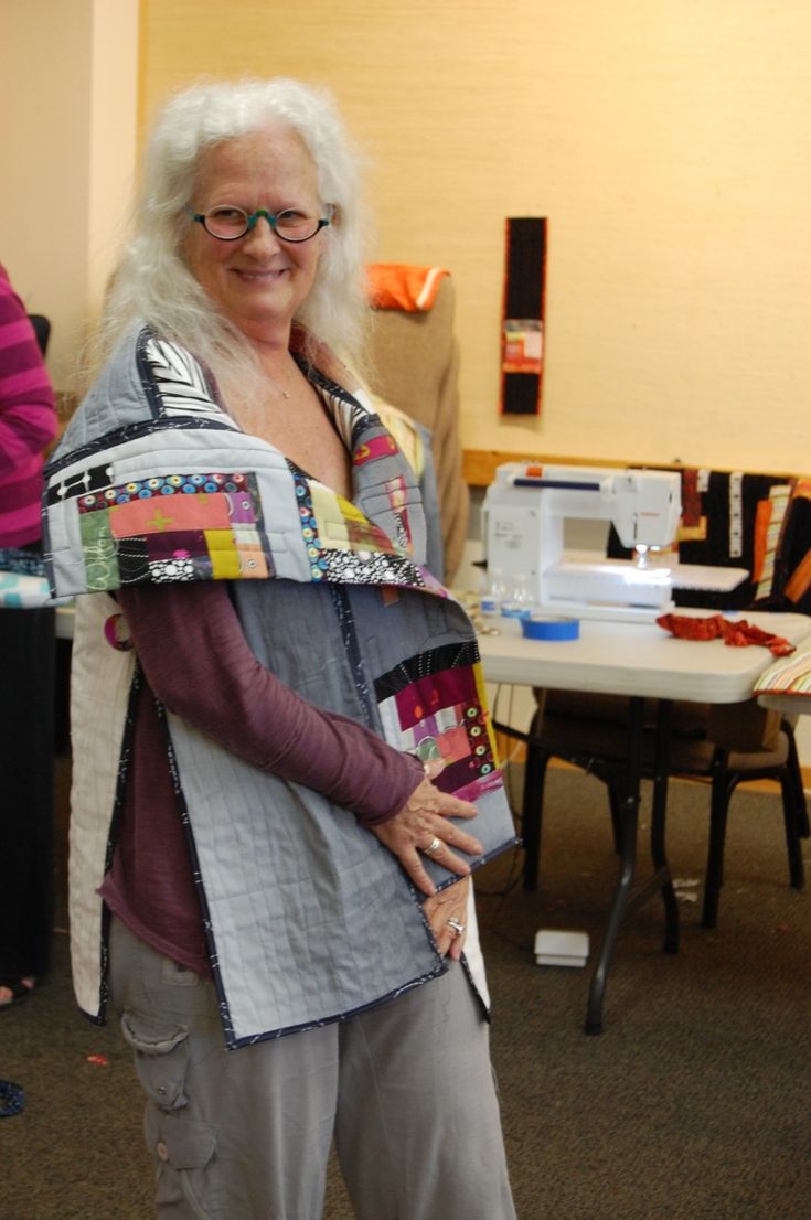 a woman with white hair and glasses is holding a piece of fabric in her hands