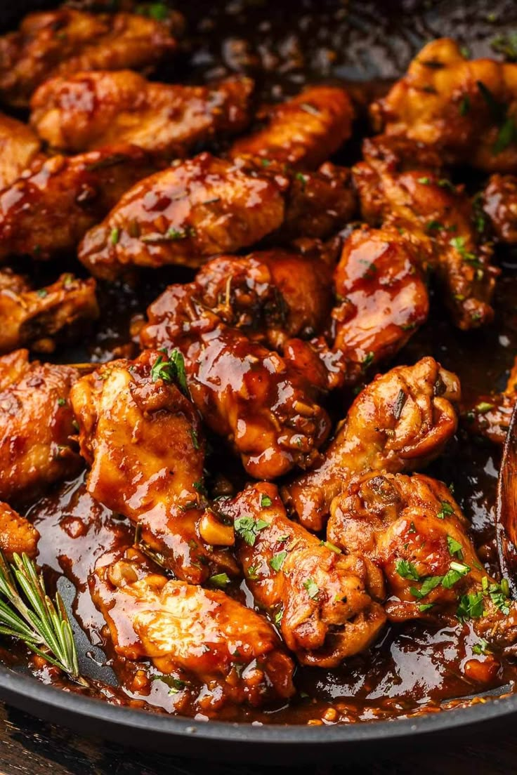 chicken wings with sauce and herbs in a skillet