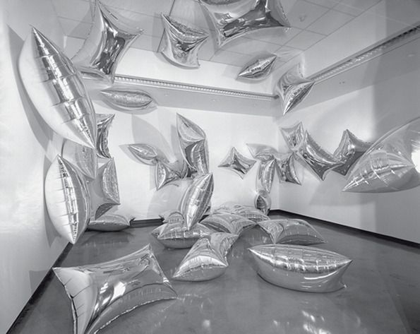 black and white photograph of balloons floating in the air over a table with silver foil on it