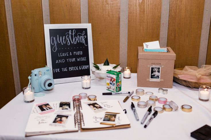 the table is set up with photos, candles and personal items for guests to sign