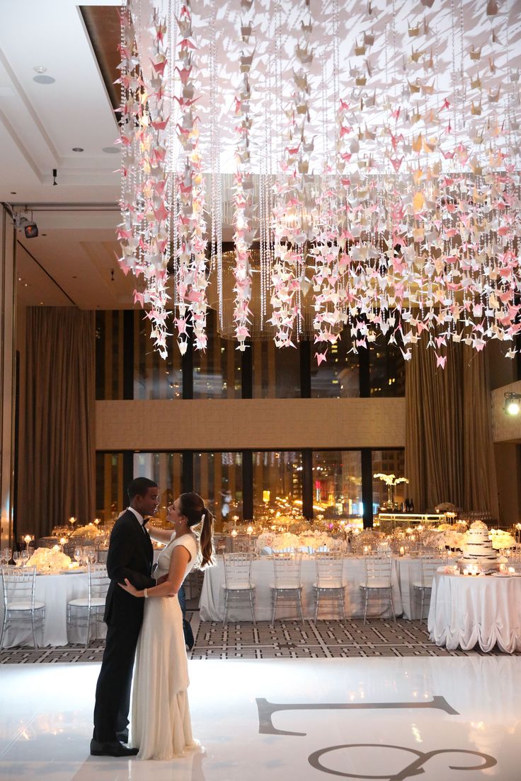 a bride and groom standing in front of a chandelier at their wedding reception