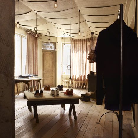 a room with wooden floors and lots of clothes hanging from the ceiling in front of a window