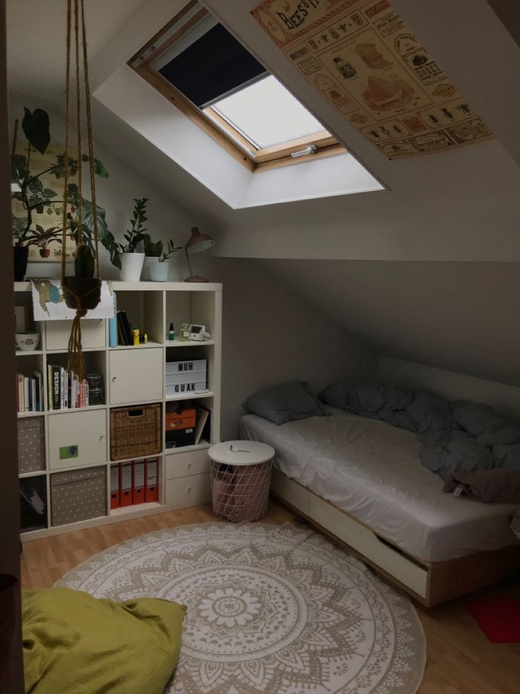 an attic bedroom with a bed, bookshelf and window