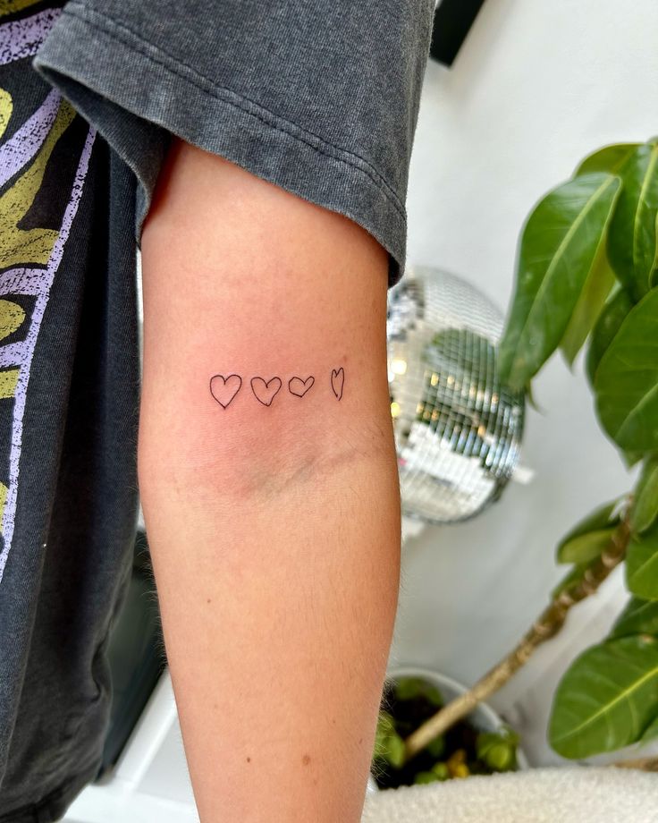 a woman's arm with three hearts tattooed on the left side of her arm