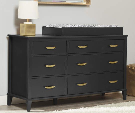 a black dresser with gold handles and knobs in a white living room next to a lamp