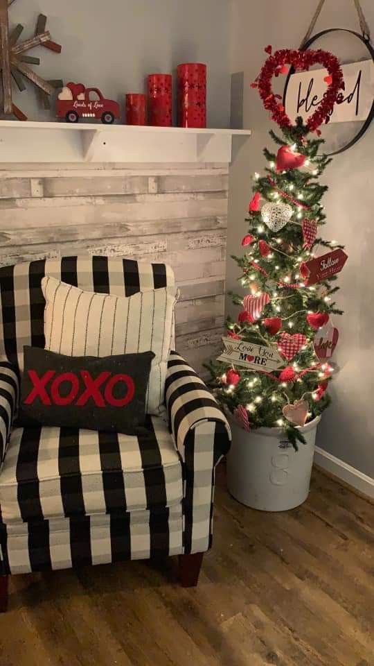 a decorated christmas tree next to a striped chair in front of a fireplace with a xoxo pillow on it