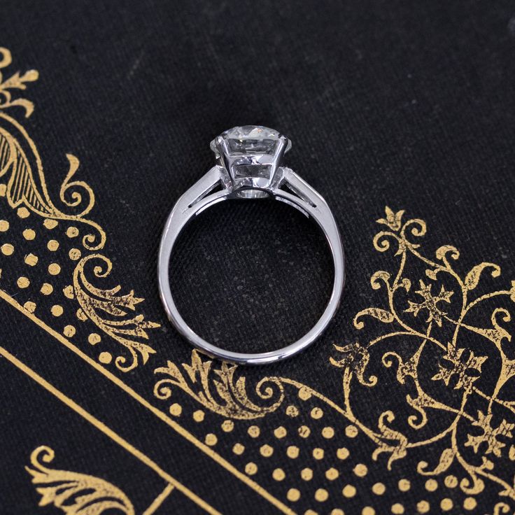 One of the most timeless and elegant solitaire styles - a simple and clean-lined style with tapered baguettes on the shoulders, allowing the central diamond to remain the main attraction. This ring showcases a stunningly and perfectly faceted old European cut diamond with that much desired flowery facet pattern under the table, twinkling softly with each movement. Sharp contrast zones which appears to be twinkling on and off with each movement, and a great higher color and clarity combo to bot! Moissanite Solitaire Baguette Cut Wedding Ring, Classic Radiant Cut Solitaire Diamond Ring, Classic Solitaire Jewelry With Radiant Cut, Classic Radiant Cut Diamond Ring, Anniversary Diamond Ring With Solitaire Baguette Cut, Anniversary Solitaire Diamond Ring With Baguette Cut, Anniversary Solitaire Diamond Ring Baguette Cut, Formal Classic Radiant Cut Diamond Ring, Baguette Cut Solitaire Diamond Anniversary Ring