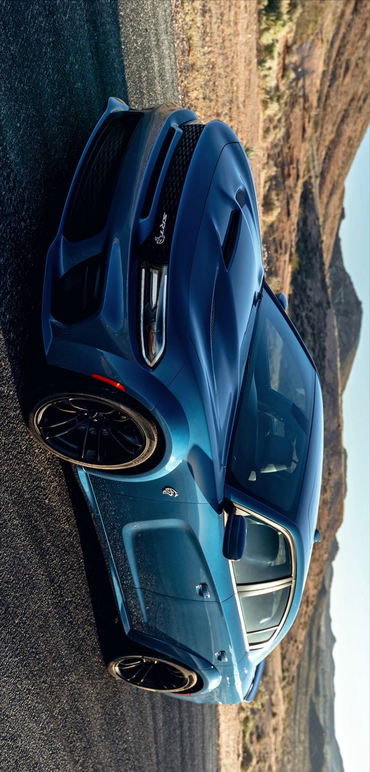 a blue sports car parked on the side of a road next to a mountain range