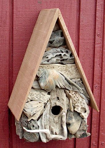 a bird house hanging on the side of a red building with shells and other things in it