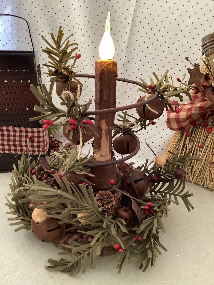 a candle that is sitting on top of a christmas wreath with pine cones and berries