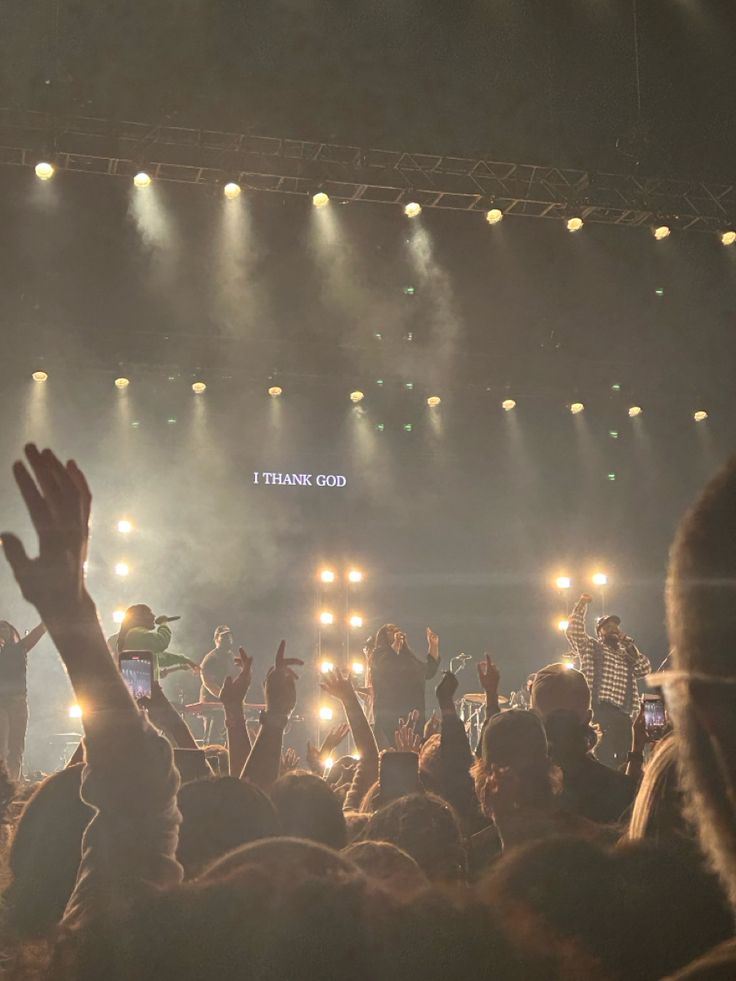 a group of people standing on top of a stage with their hands in the air