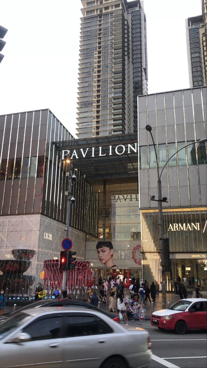 a car driving down the street in front of a tall building with a sign that says pavilion on it