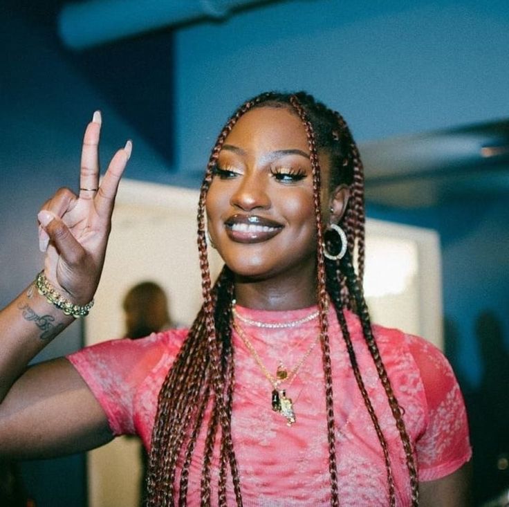 a woman with long braids making the peace sign