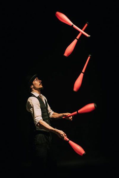 a man juggling red arrows in the dark