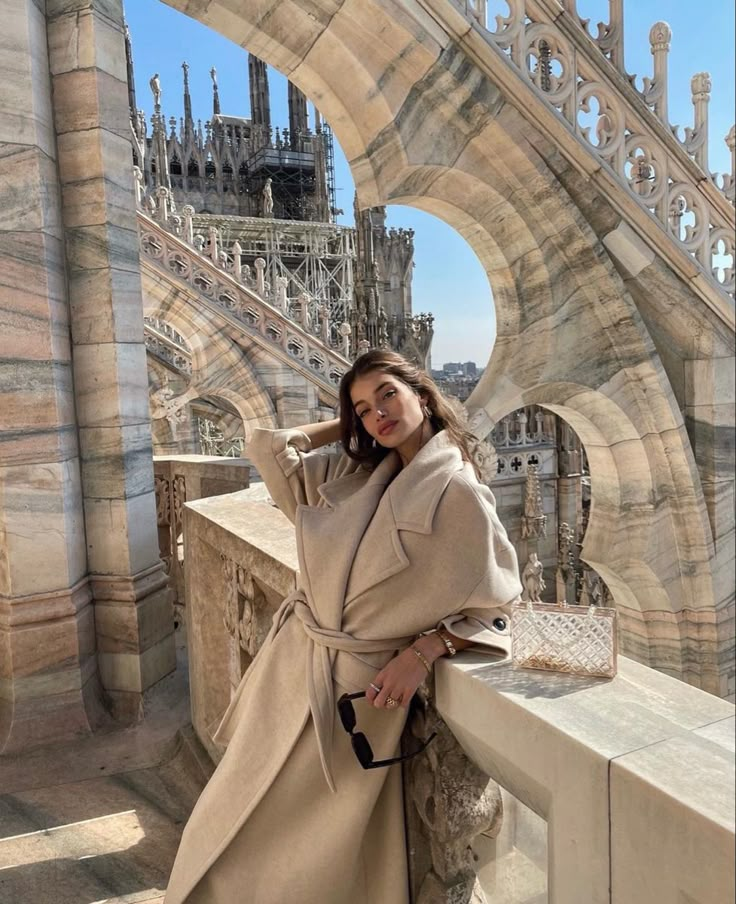 a woman standing on top of a bridge wearing a trench coat