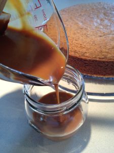 someone pouring caramel sauce on top of a cake