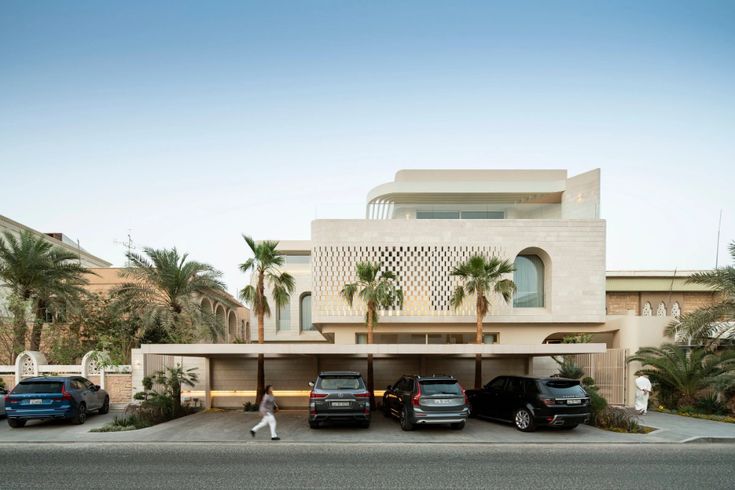 three cars parked in front of a large building with palm trees on the other side