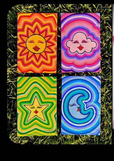 four square paintings with sun, moon and clouds on them in the grass by itself