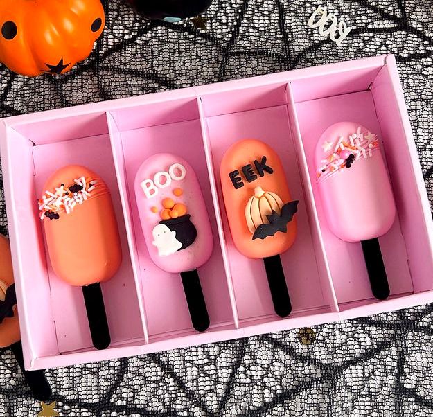 four pops are in a pink box with halloween decorations on the top one is for boo