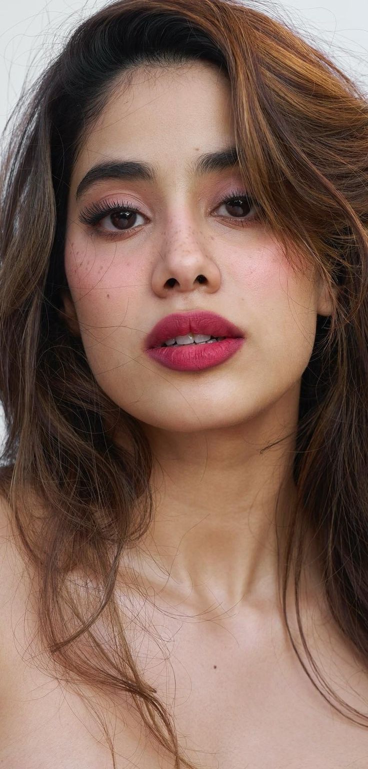 a woman with long brown hair and red lipstick is posing for the camera while wearing a strapless top