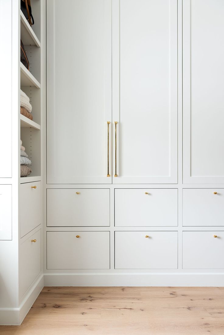 a white closet with gold handles and drawers