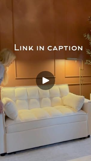 a woman is standing in front of a white couch with the caption link in caption