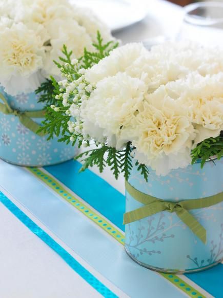 two vases filled with white flowers sitting on top of a blue and white table