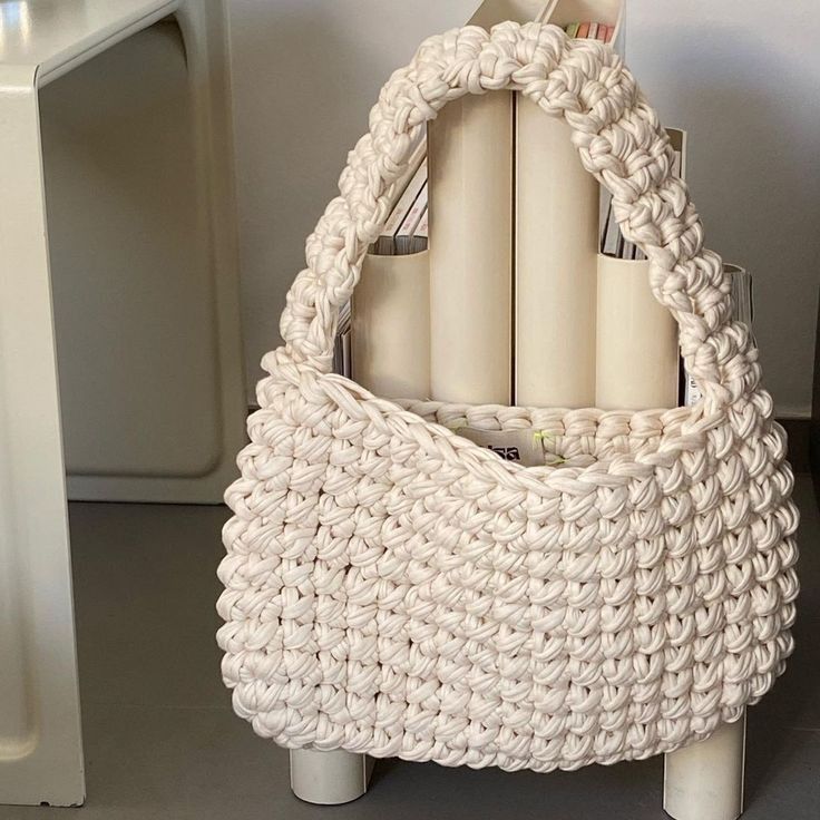 a crocheted bag sitting on top of a table next to a white chair