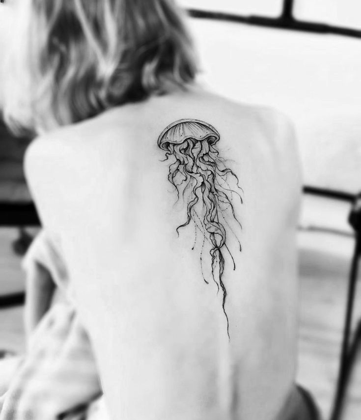 a woman with a tattoo on her back that has a jellyfish in the water