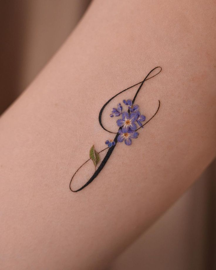 a small tattoo on the arm of a woman with blue flowers in it's center