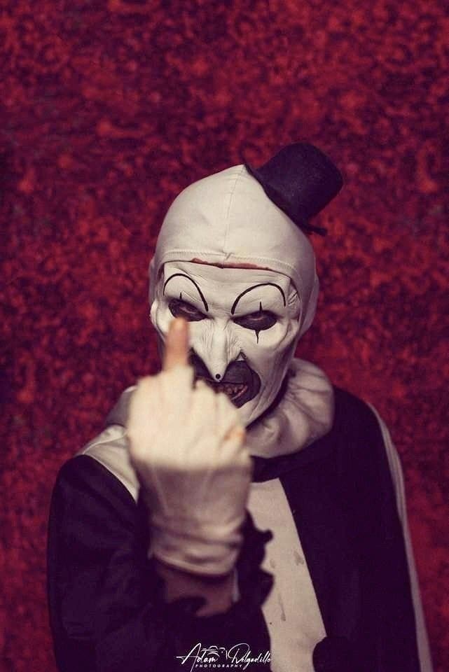 a person wearing a white mask and pointing to the side with their finger in his mouth