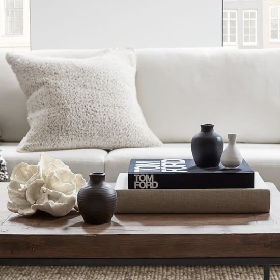 a coffee table with books and vases on it in front of a white couch