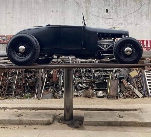 an old model t car is on display in front of a junk yard full of junk