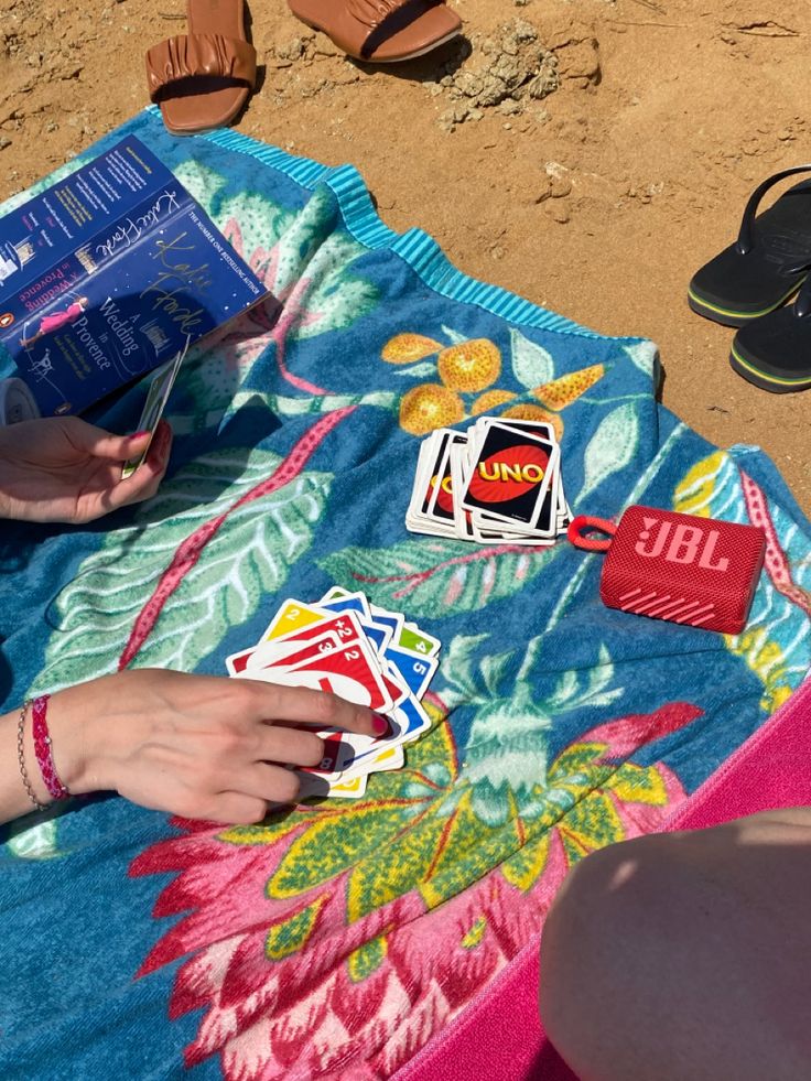 a woman laying on the beach with her flip flops and some stickers in her hand