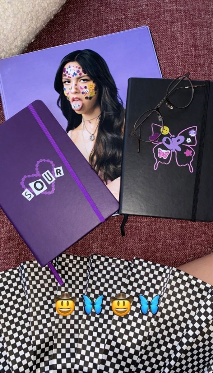 a table topped with two notebooks covered in face paint next to an empty binder