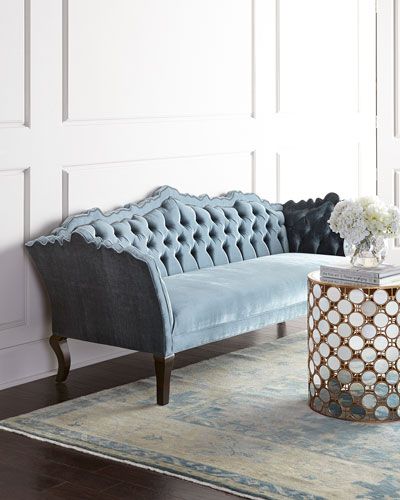 a blue couch sitting on top of a wooden floor next to a white vase filled with flowers