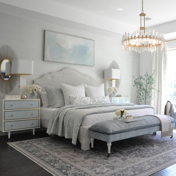 a bedroom with a large bed, chandelier and two nightstands in it