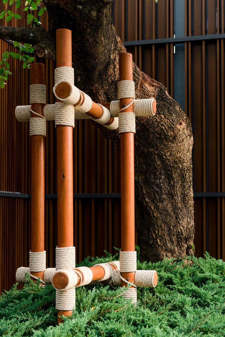 a group of wooden poles sitting on top of grass covered ground next to a tree