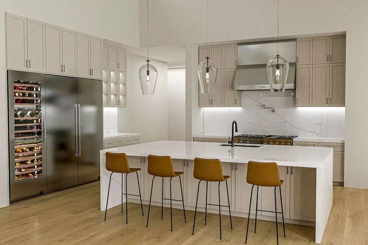 a kitchen with white counter tops and yellow chairs in front of an island that has wine racks on it