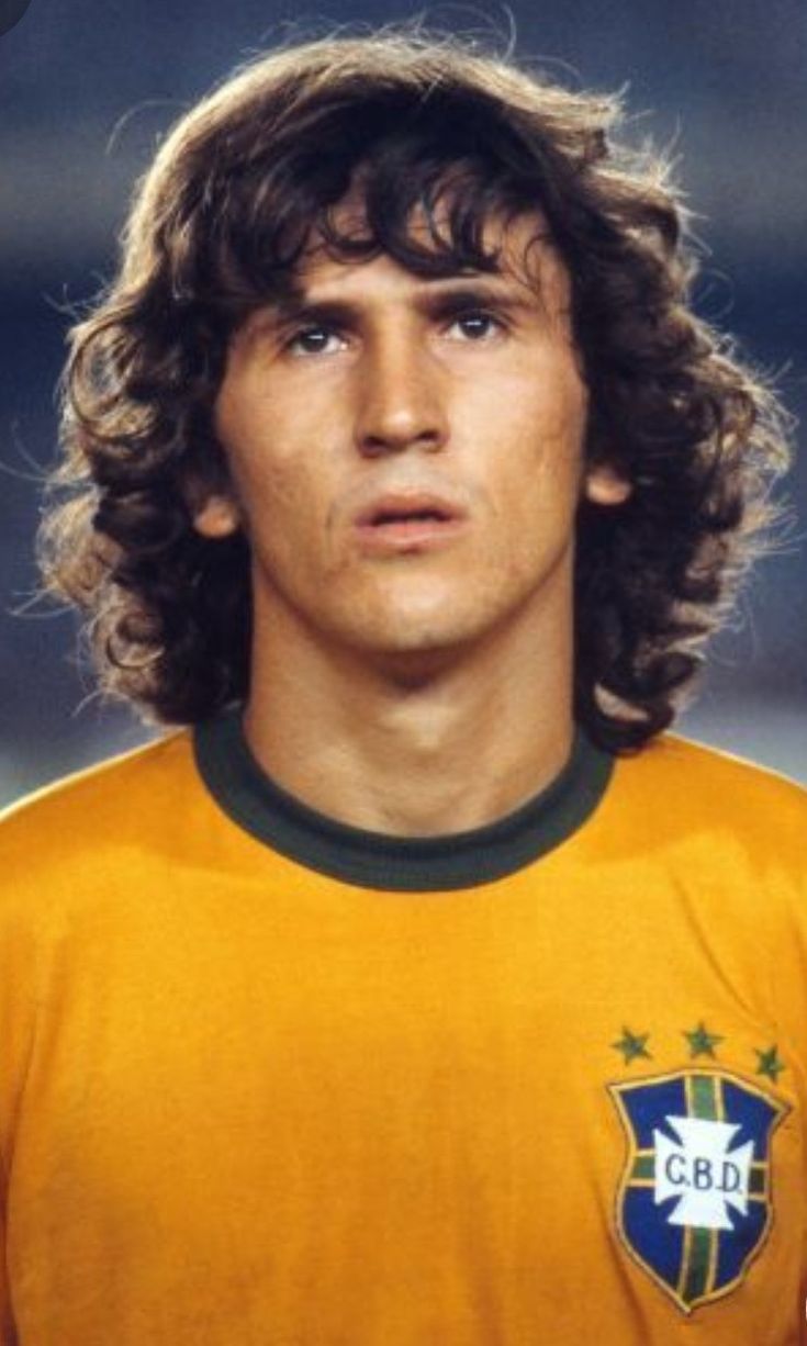 a young man with long hair wearing a yellow soccer jersey and looking off to the side