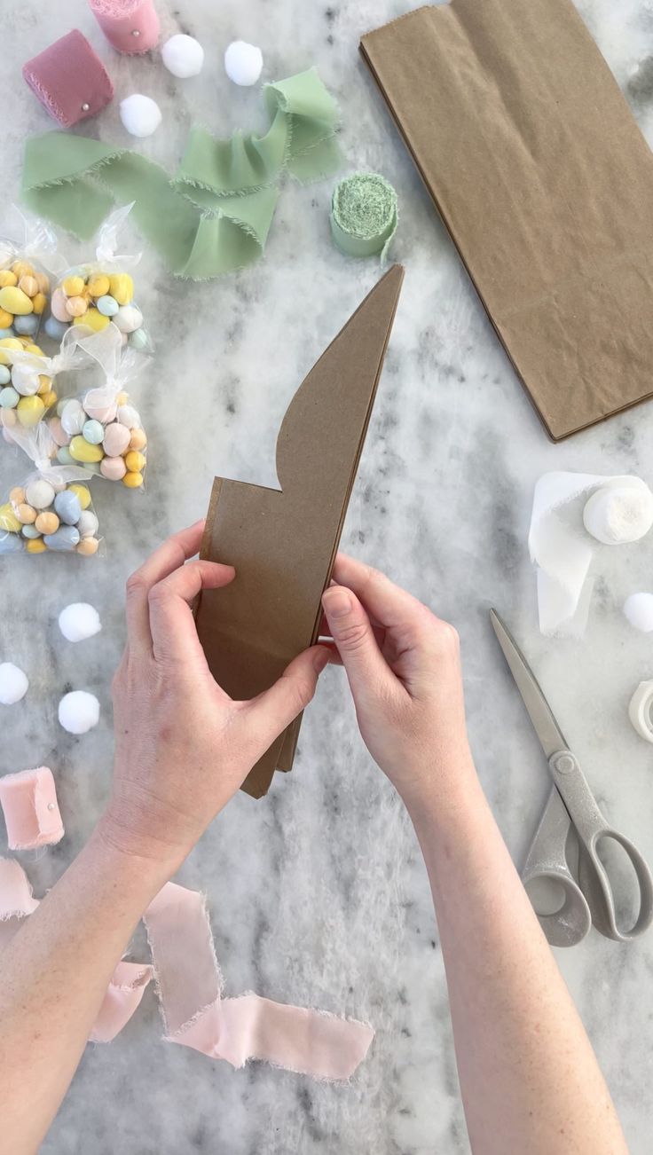 someone is cutting up a piece of paper with scissors and other crafting supplies on the table