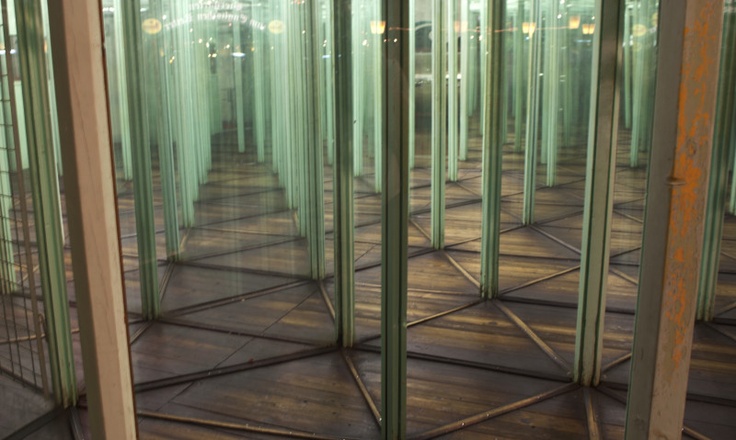 an empty room filled with lots of glass partitions in the middle of a wooden floor