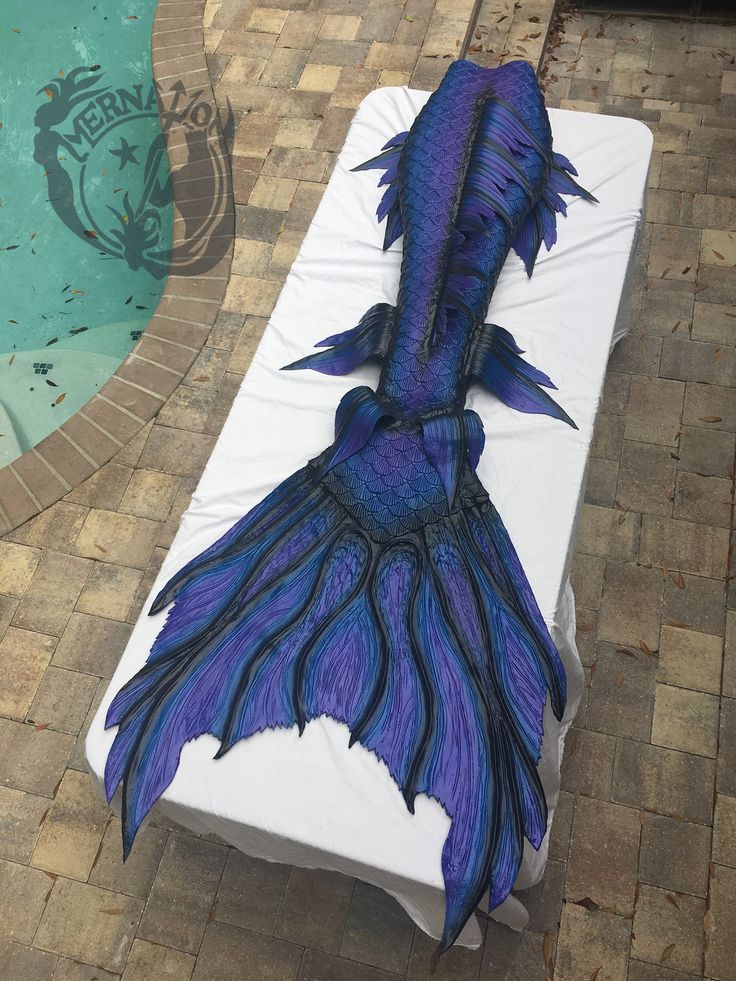 a blue and black dragon tail laying on top of a white mattress next to a swimming pool