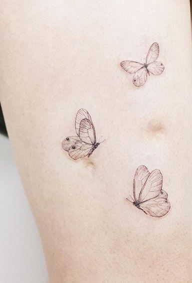 three small butterflies on the back of a woman's thigh, one is black and white